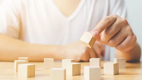 Person plukker opp en trekloss fra et bord med flere klosser.